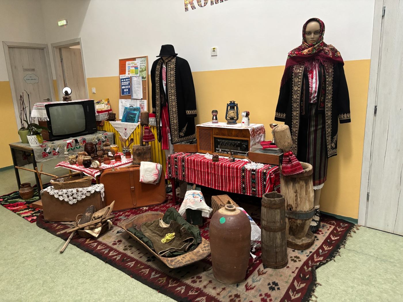Colț de casă tradițională în muzeul școlii, cu costume și scoarțe